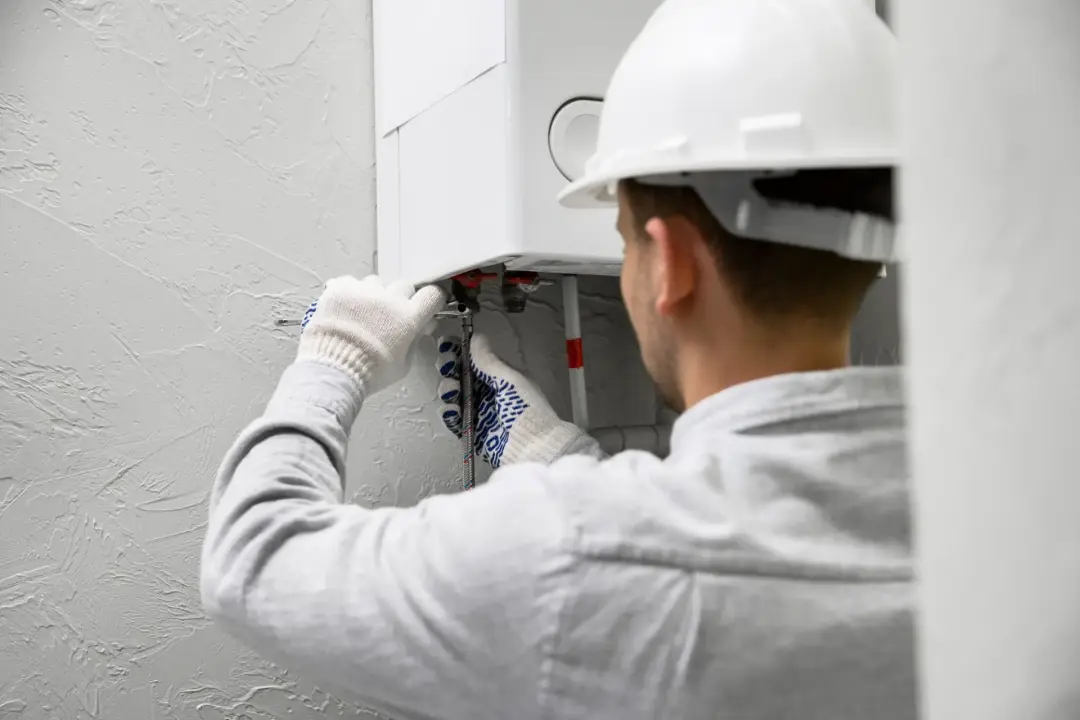 Heating engineer carrying out an annual boiler service